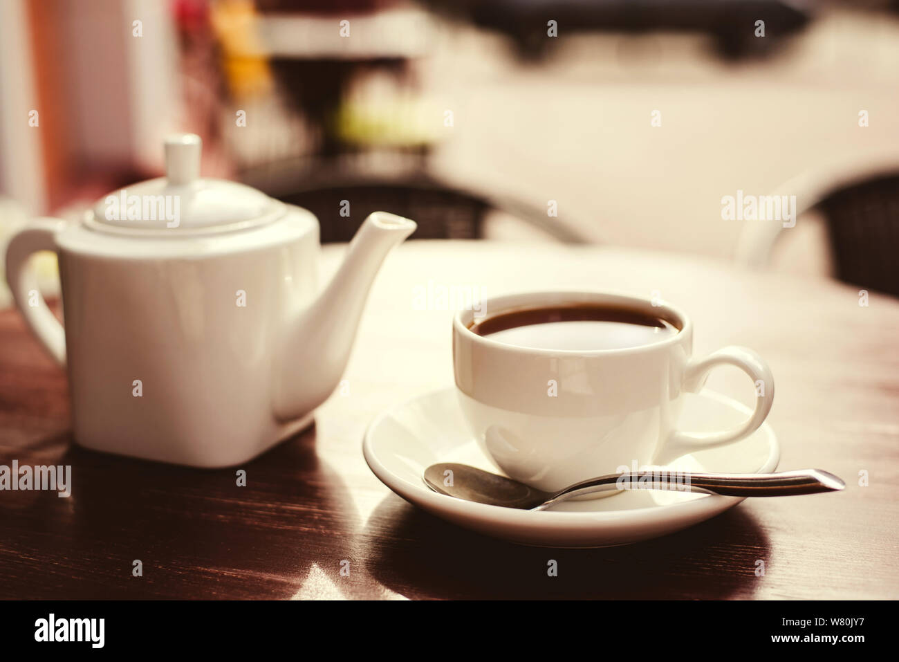Teapot and a cup of tea on a wooden table in a summer cafe Stock Photo
