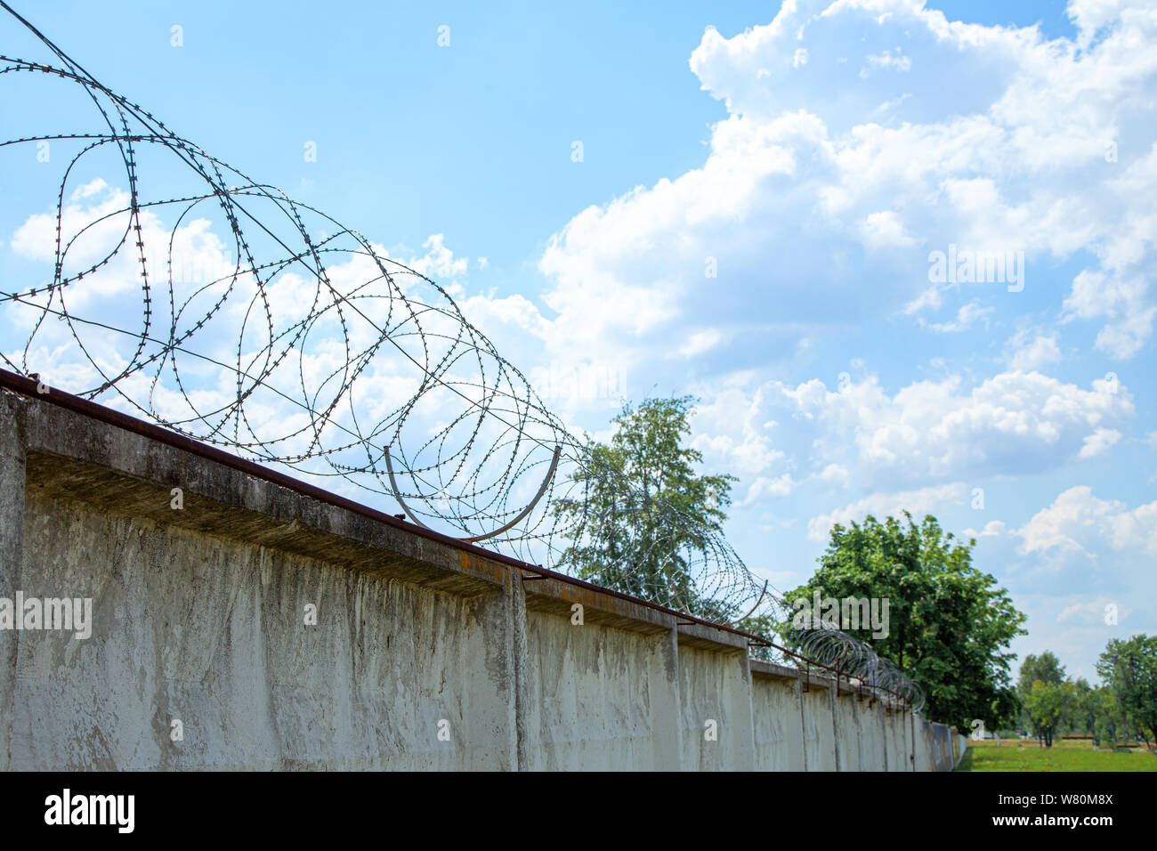 Concrete wall with barbed wire against the sky with clouds Stock Photo ...