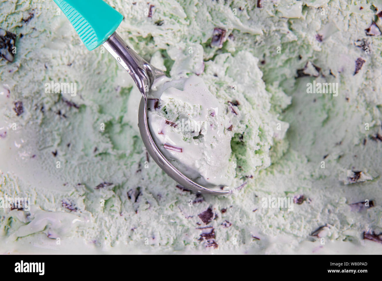 Top view of mint flavour ice cream with chocolate flakes in box. Focus on ice cream in scoop. Stock Photo