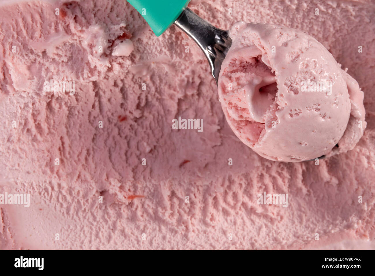 Top view of strawberry flavour ice cream with scoop in box. Focus on scoop with ice cream. Stock Photo