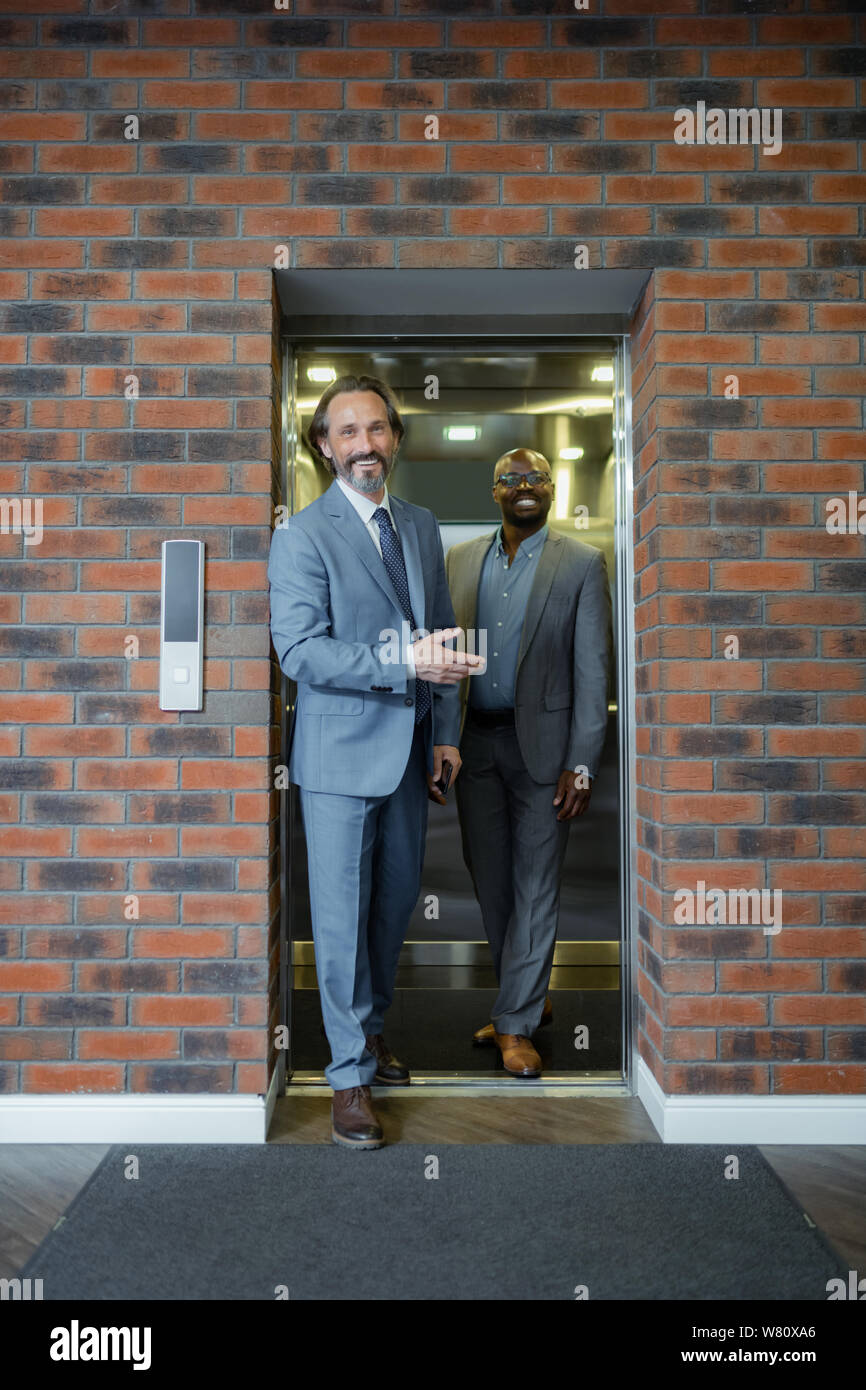 Two businessmen leaving elevator smiling before negotiation Stock Photo
