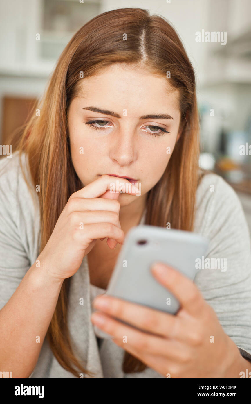 brunette teenager girl looking at the screen of her smartphone Stock Photo