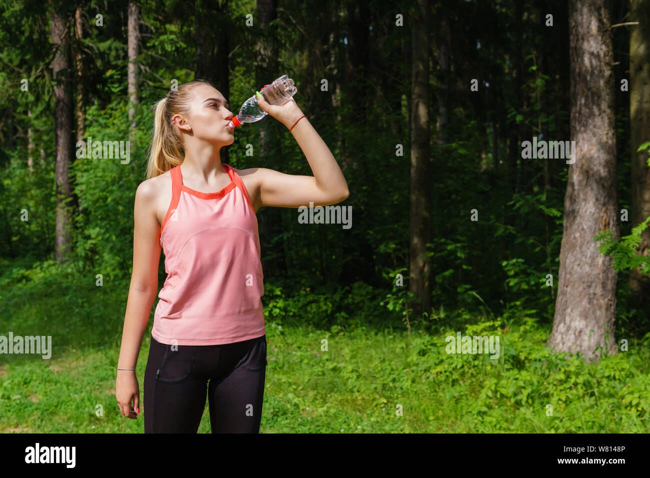 Woman Runner Quenches Thirst From A Plastic Bottle While Jogging