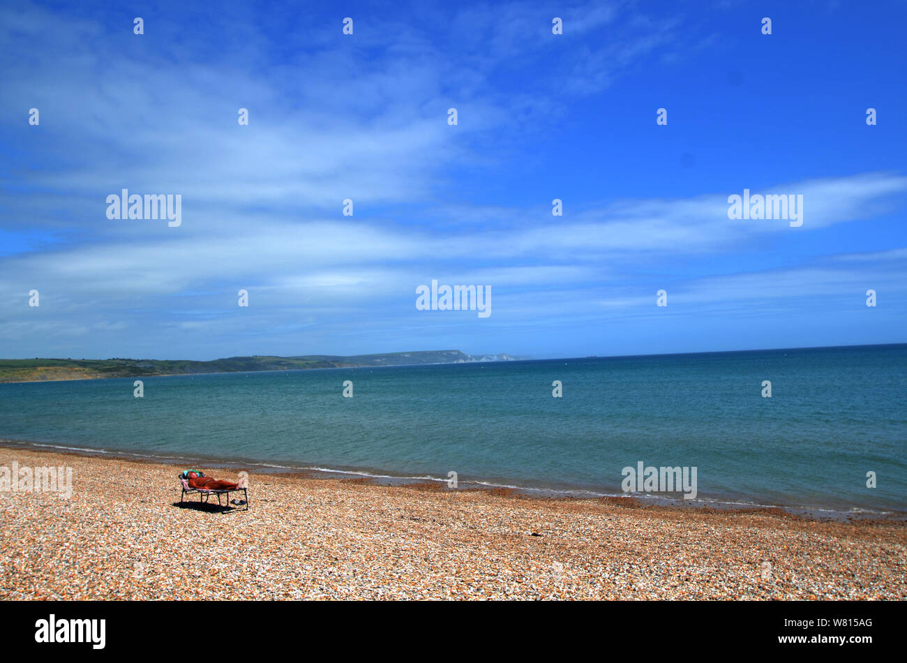 A sunbather enjoying the hot weather along the beach at Weymouth, Dorset, United kingdom Stock Photo