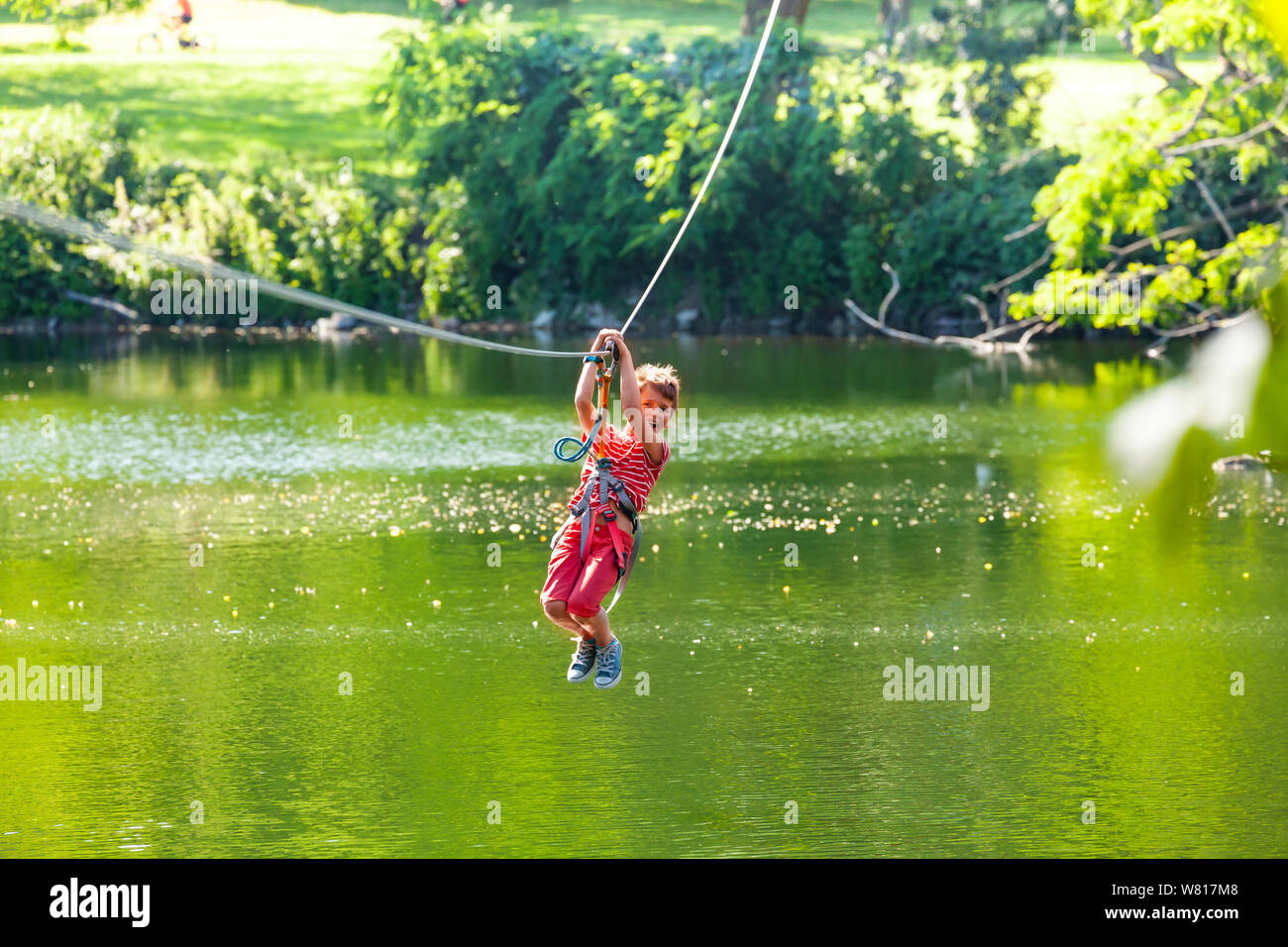 Happy child slide zip line with trolley over lake Stock Photo - Alamy