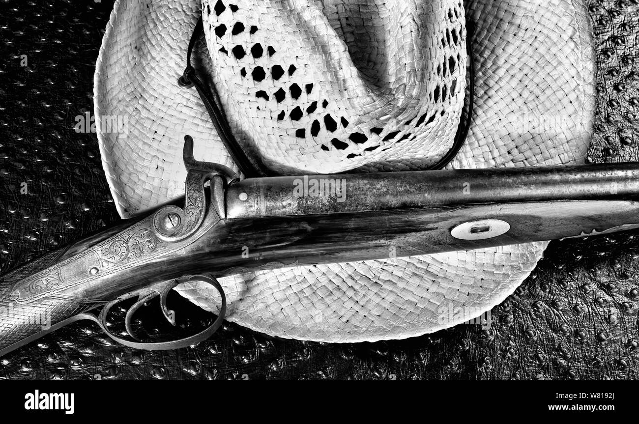 Antique shotgun and old straw cowboy hat in black and white. Stock Photo