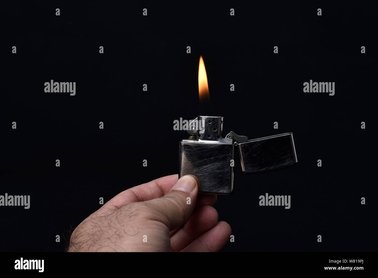 holding lighter lit on black background Stock Photo - Alamy
