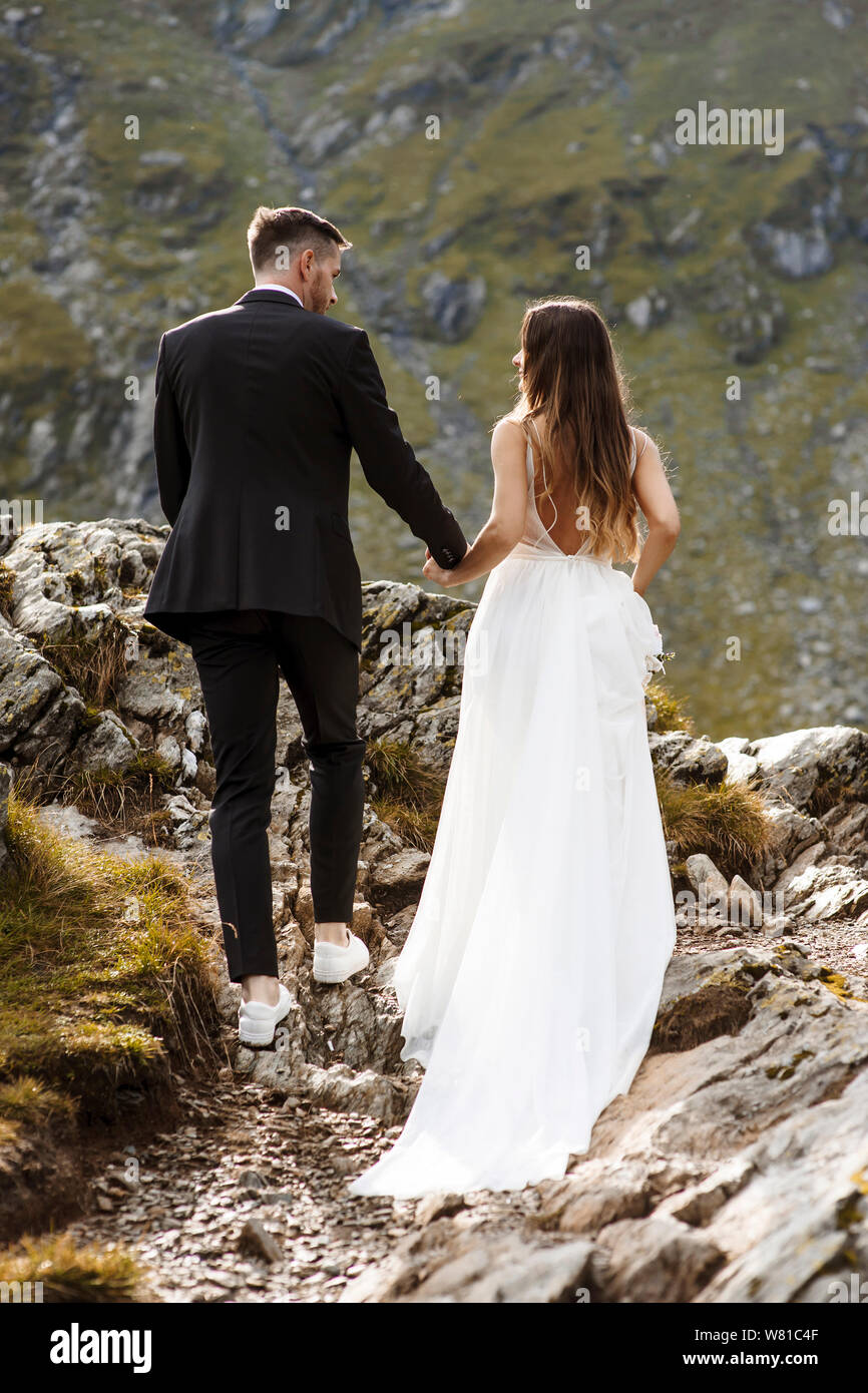 Full length and back view of a young wedding couple walking through the ...