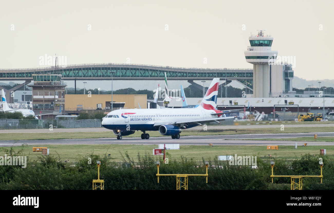 A British Airways Airbus A320-232 turns off the runway in front of the air traffic control tower after landing at London Gatwick Airport. Stock Photo