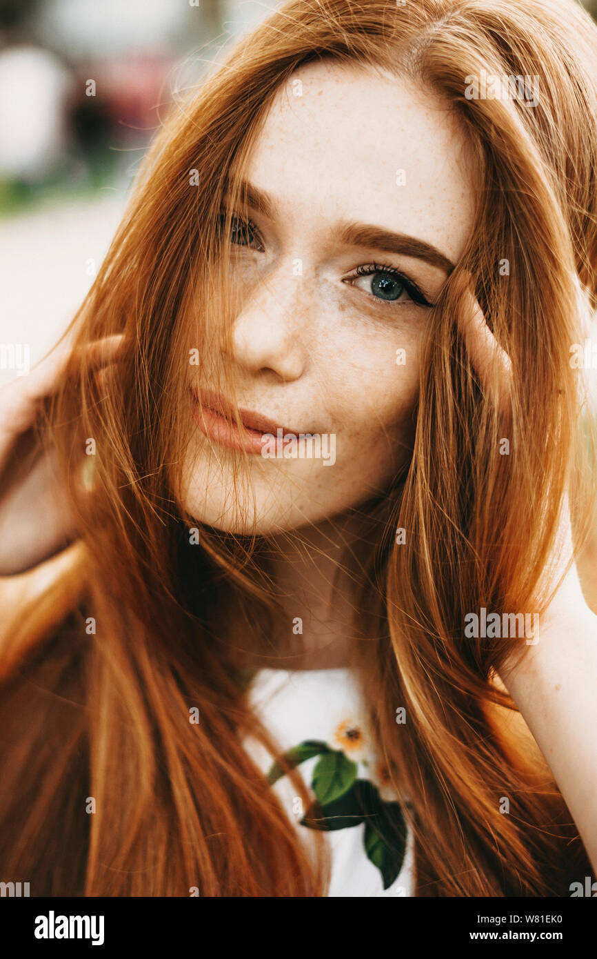 Close up portrait of a amazing red haired girl with freckles and green eyes  looking at camera smiling touching her red hair outside Stock Photo - Alamy