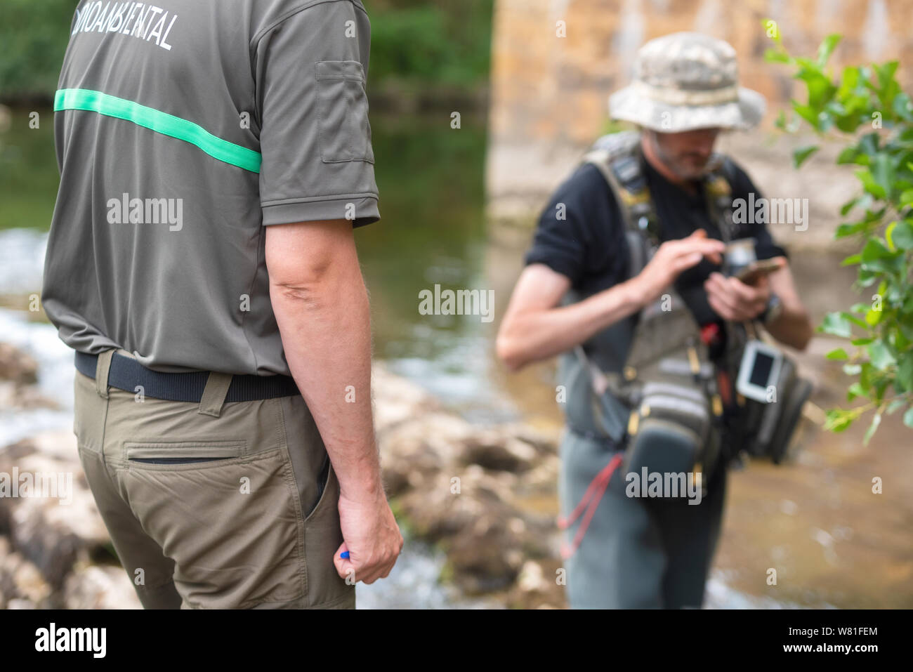 Police officer or Ranger checking fisherman license in river. Fishing inspection. Law .  Stock Photo