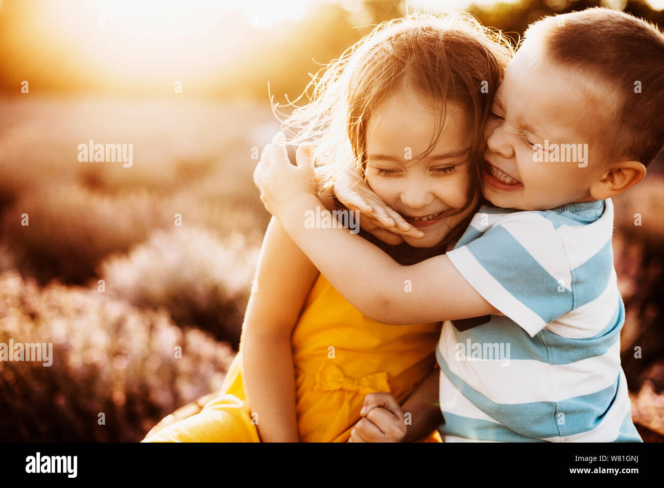 Little brother and sister by the lake hugging tight and beeing