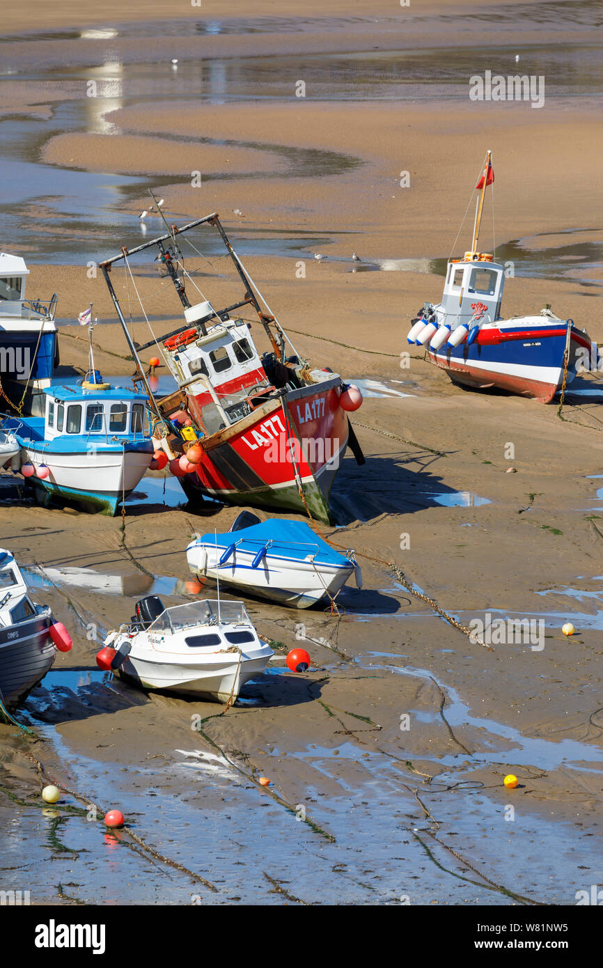 Fishing boats beached at low tide in the harbour at Tenby, a walled seaside town in Pembrokeshire, south Wales coast on the west of Carmarthen Bay Stock Photo