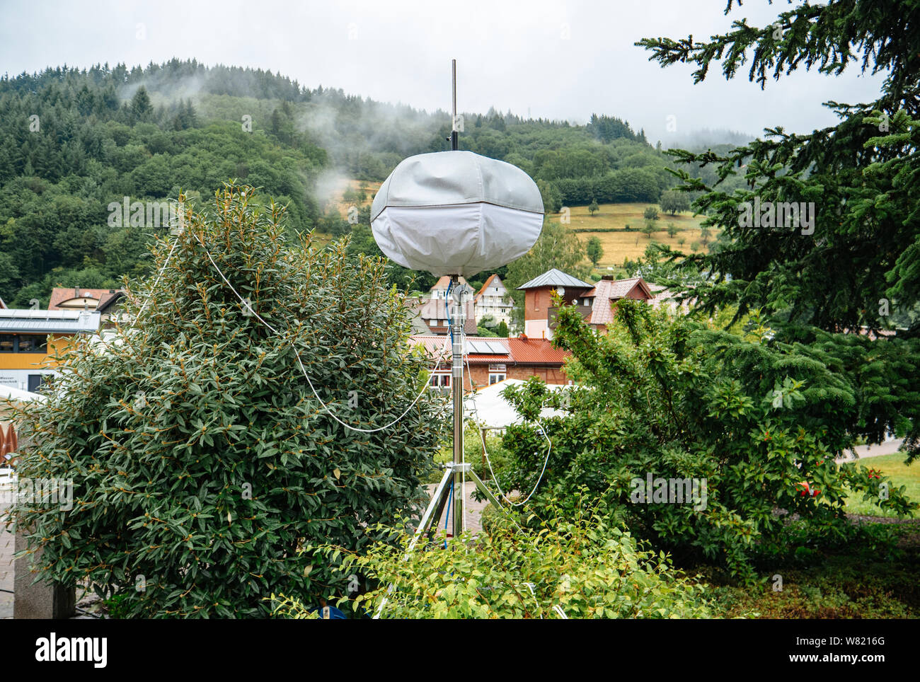 Mobile meteo station with houses of Ottenhofen im Schwarzwald, Germany in the background and green forest covered with fog Stock Photo