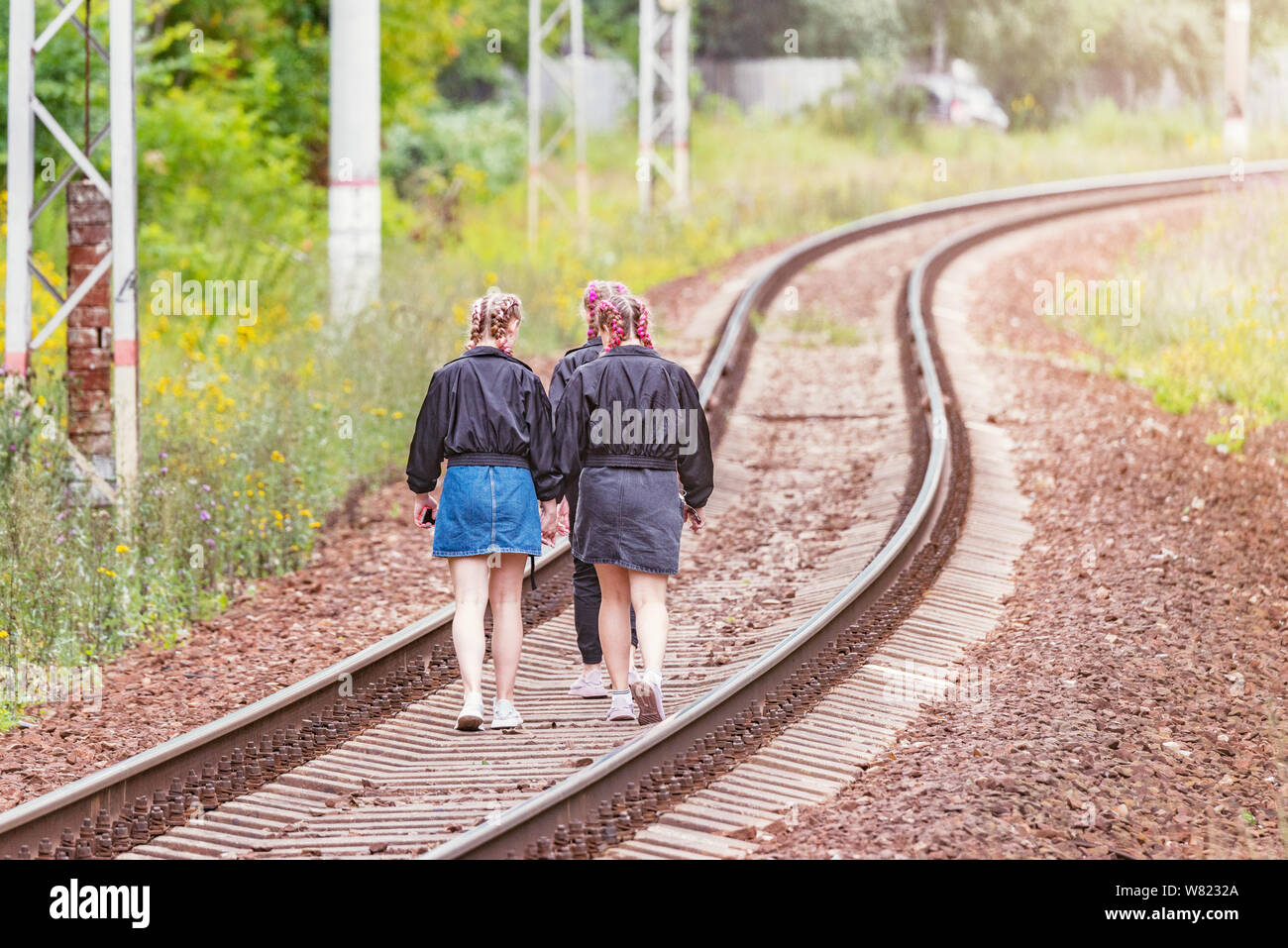 Three young girls walk on the railway track at evening time Stock Photo