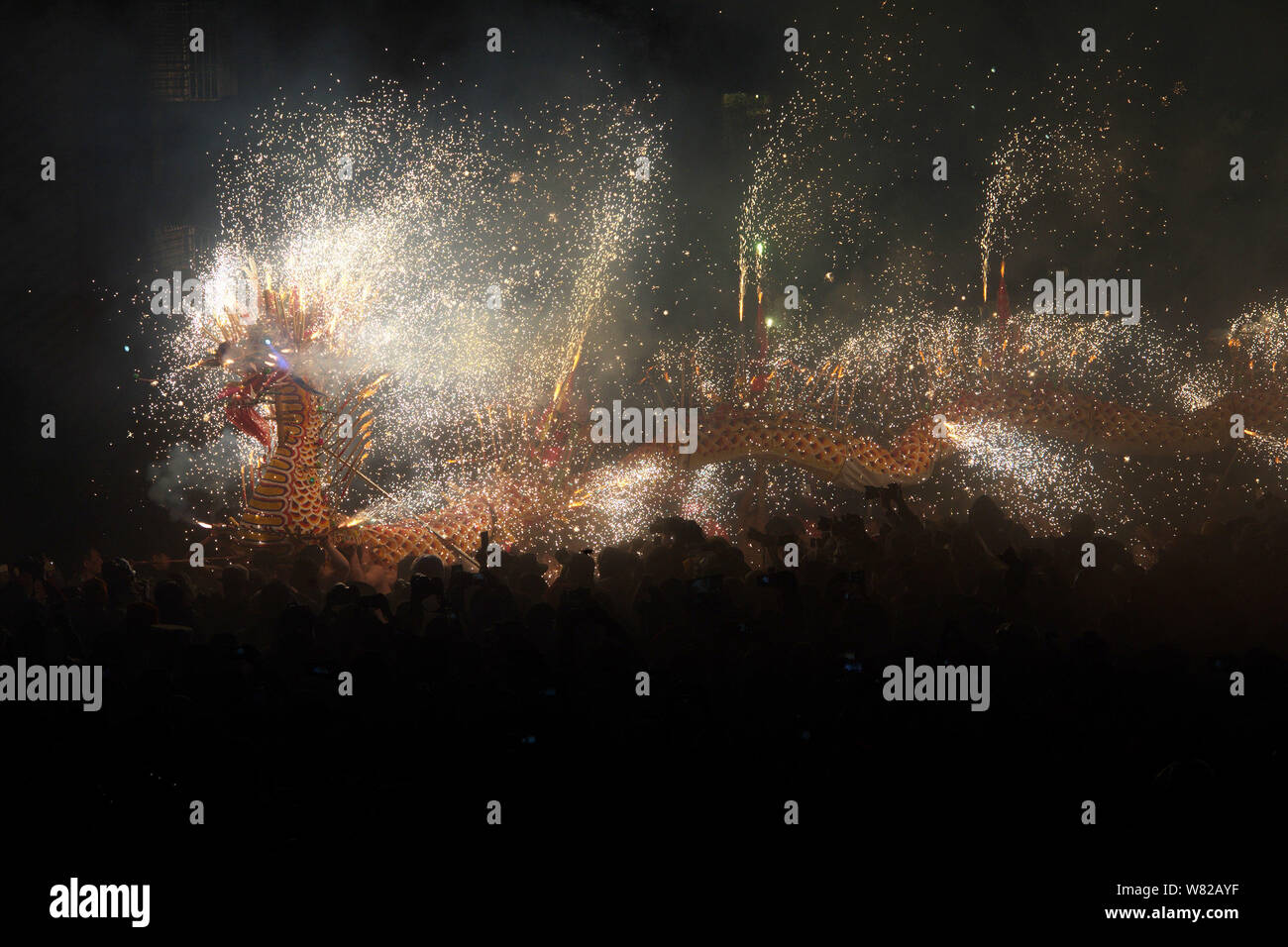 Chinese entertainers perform a dragon dance in sparks of fireworks to ...