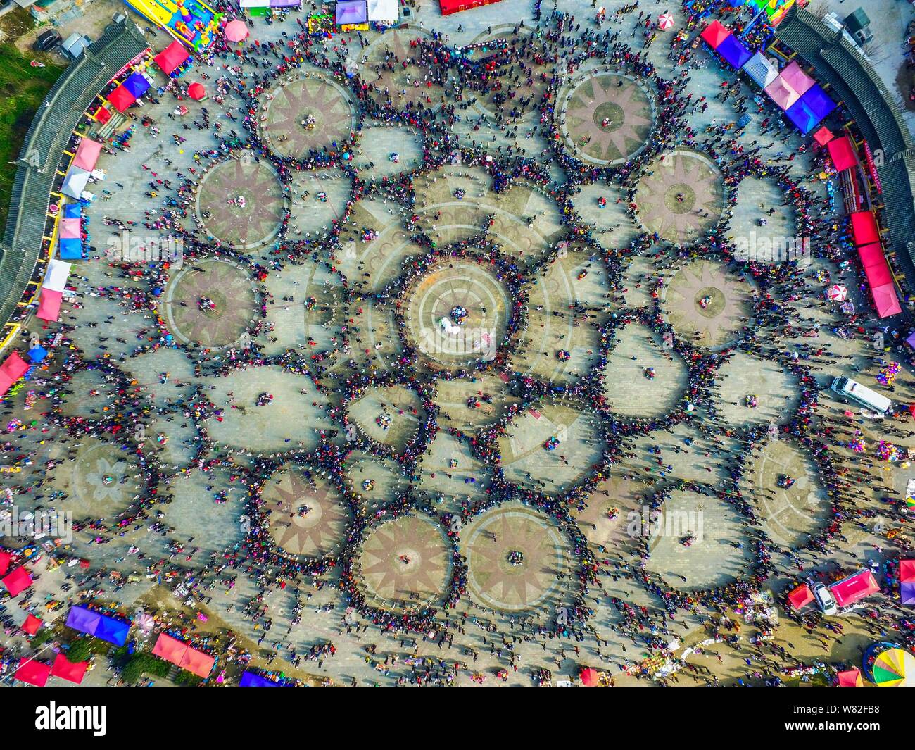 Aerial view of Chinese women of Miao ethnic minority dressed in traditional silver-decorated clothes and headwears performing a group dance in circles Stock Photo