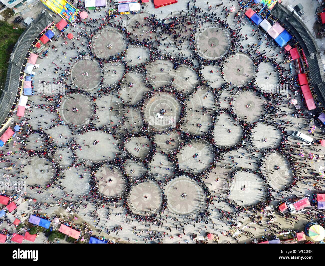 Aerial view of Chinese women of Miao ethnic minority dressed in traditional silver-decorated clothes and headwears performing a group dance in circles Stock Photo
