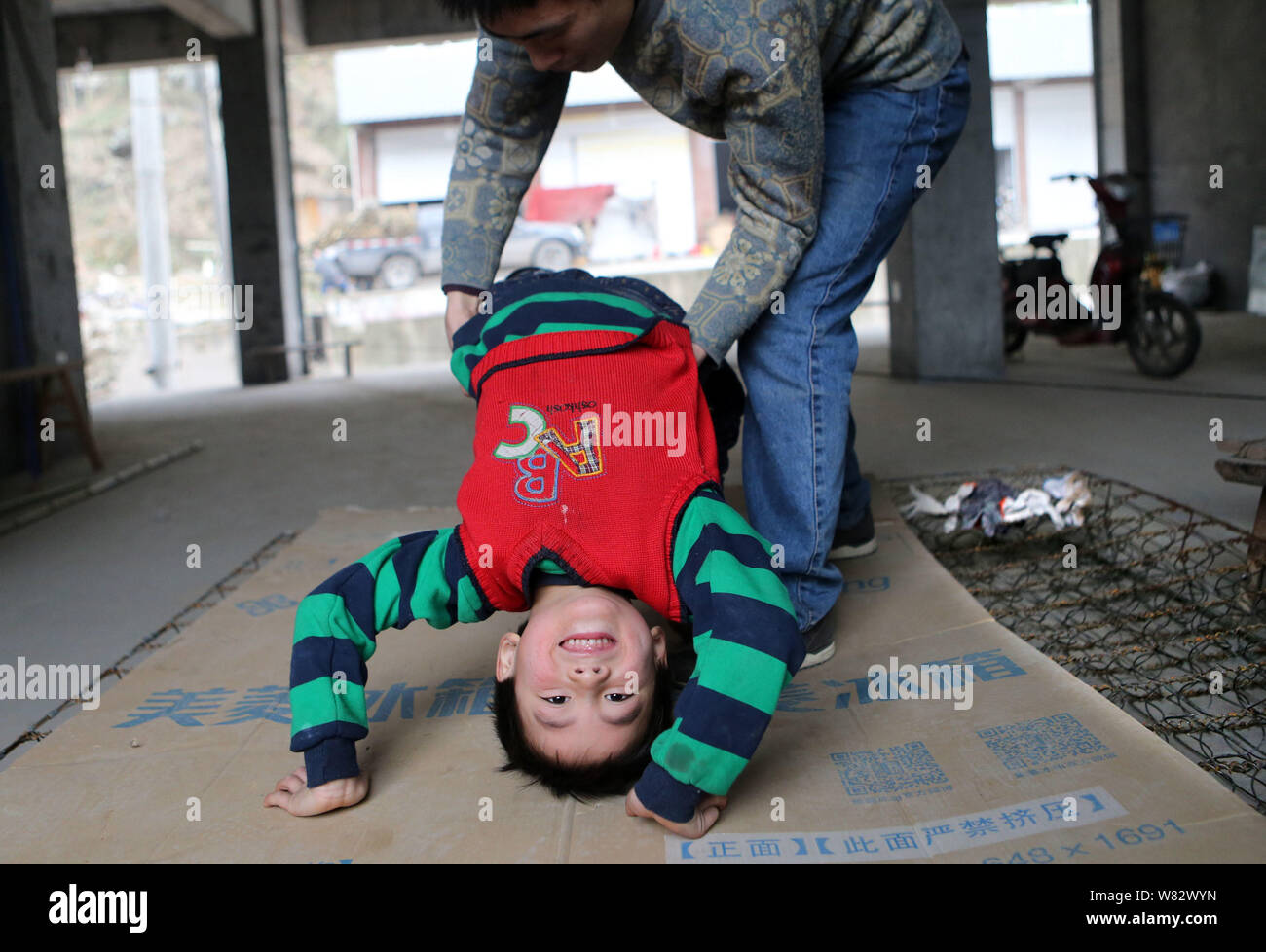 5-year-old Chinese boy Zhang Wang, who was trained to walk on wires by his father, practices bending backward into a bridge in Yuanba village, Nanjian Stock Photo