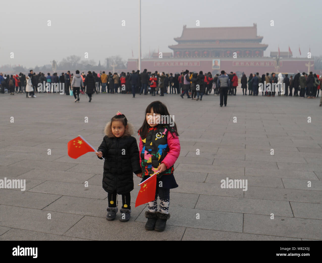 --FILE--Young girls holding Chinese national flags visit the Tian'anmen Square in heavy smog in Beijing, China, 31 December 2016.   Beijing filed 13,1 Stock Photo