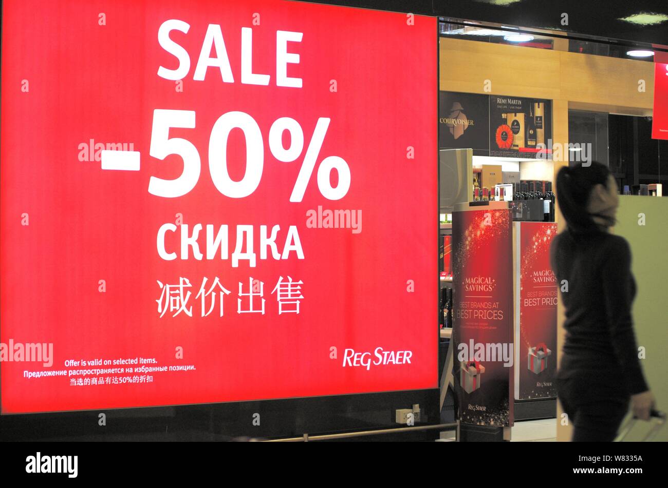 A Chinese Employee Stands Next To A Signboard Showing 50 Discount