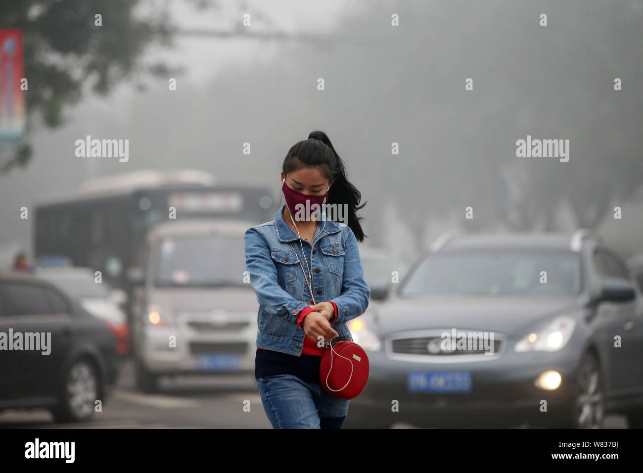 --FILE--A pedestrian wearing a face mask against air pollution walks across a road in heavy smog in Beijing, China, 14 October 2016.   Beijing's envir Stock Photo