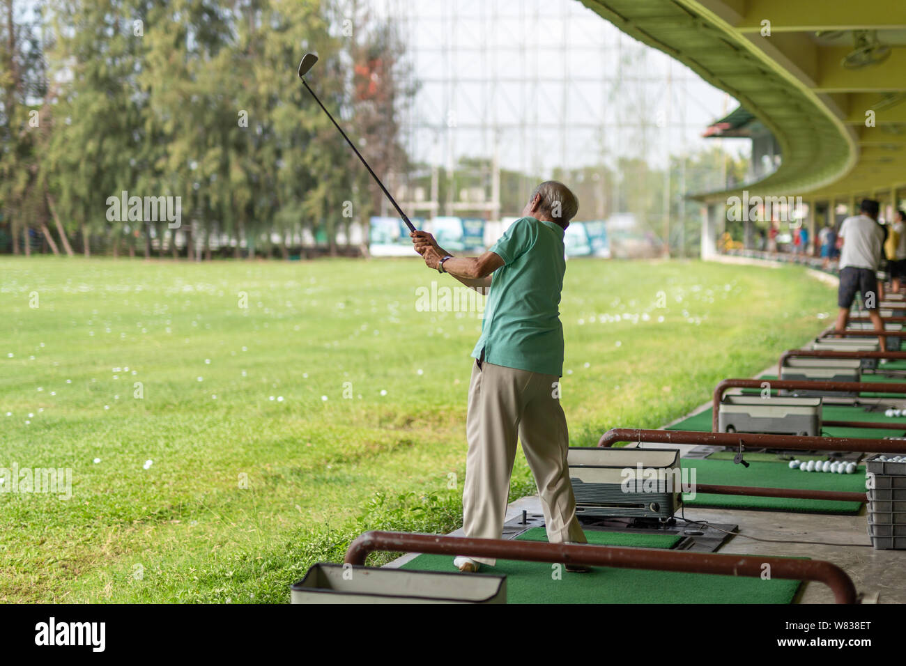 Senior man exercise practicing his golf swing at golf driving range