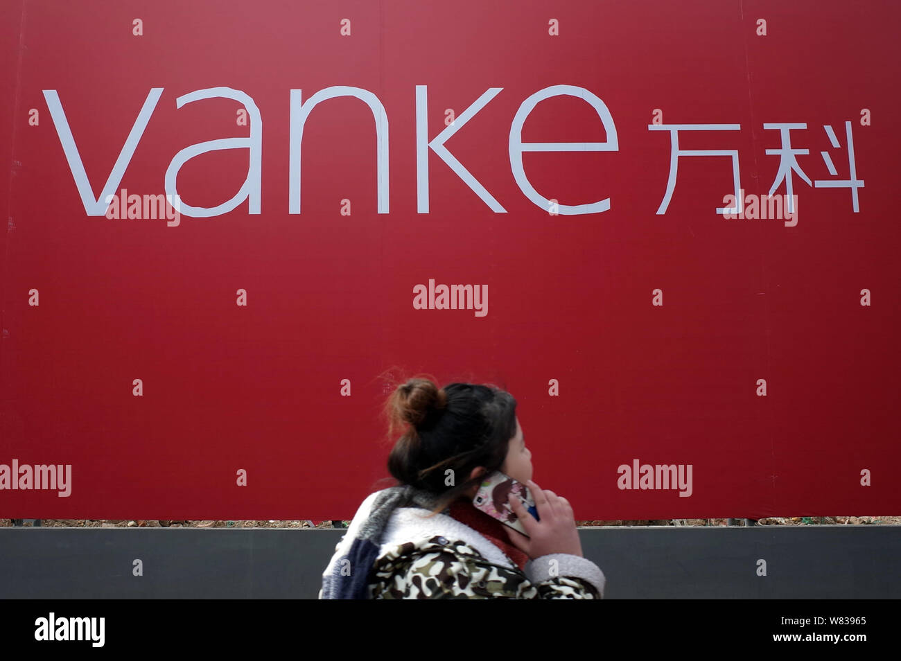 --FILE--A pedestrian walks past an advertisement for Vanke in Jinan
