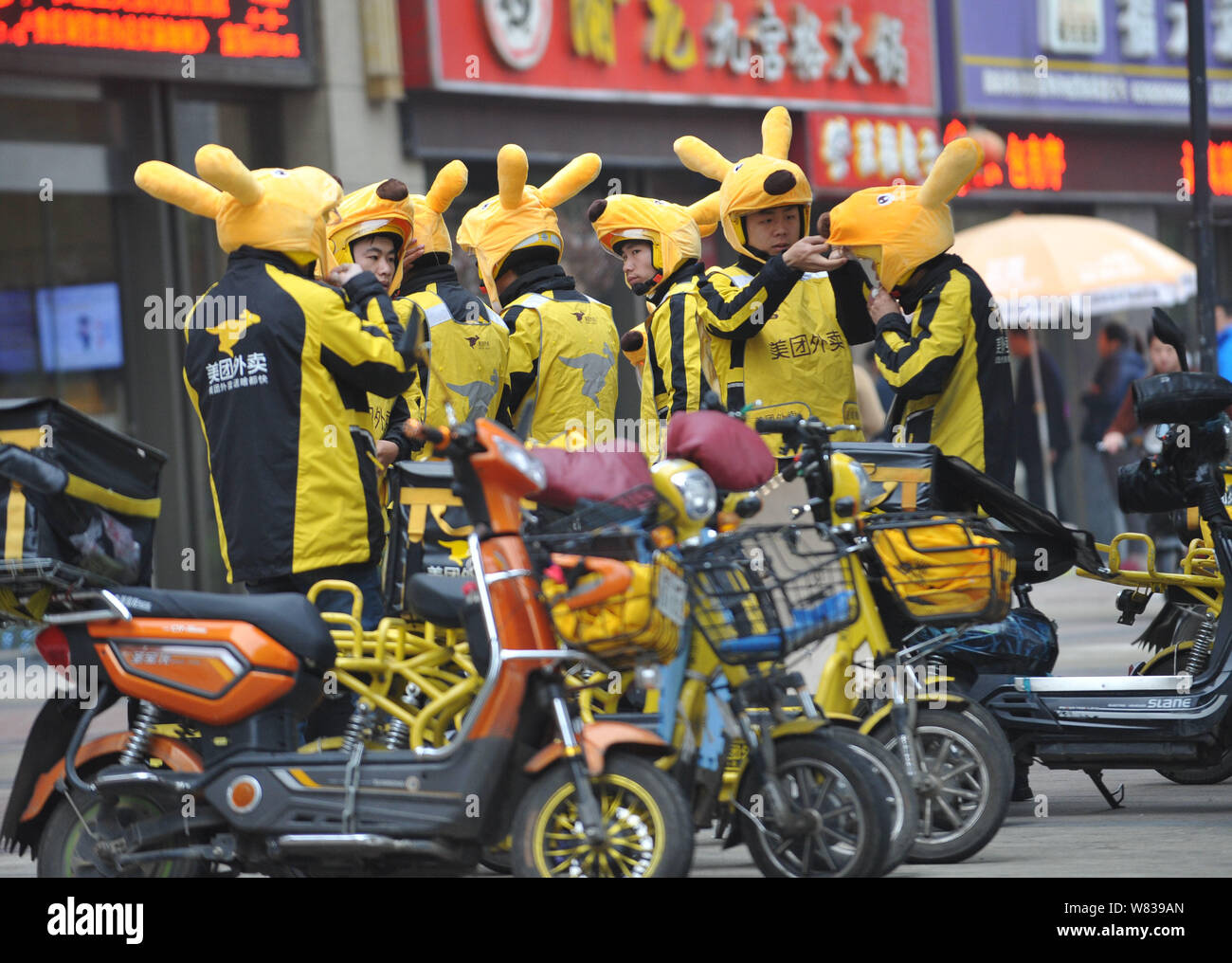 Couriers of Chinese online food delivery company Meituan put on kangaroo headgears during a morning report before delivering food on a street in Wuhan Stock Photo