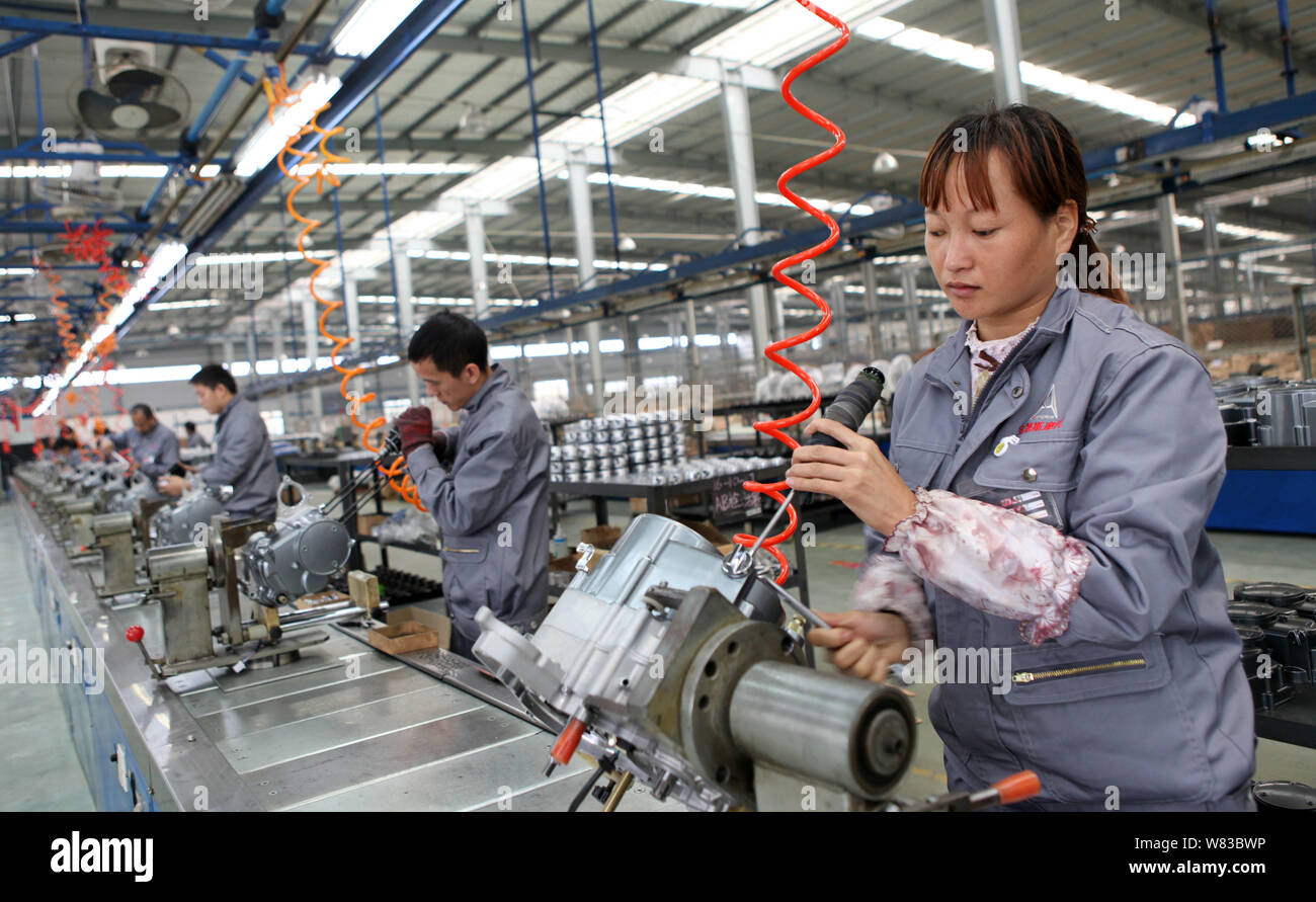 --FILE--Chinese workers assemble motorbike engines on the assembly line at a plant of a motorcycle company in Chongqing, China, 4 November 2016.   The Stock Photo