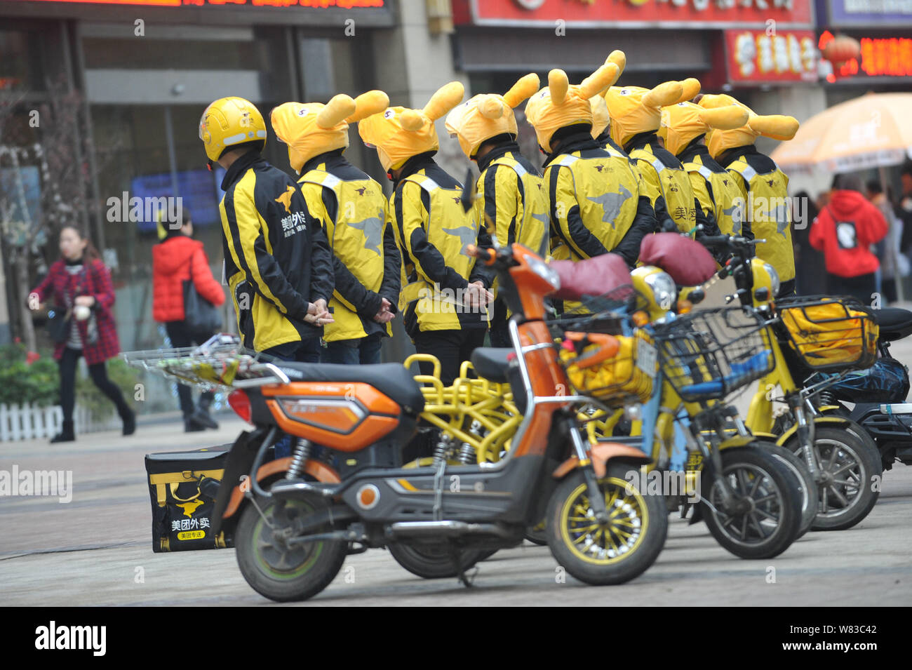 Couriers of Chinese online food delivery company Meituan wearing kangaroo headgears stand in line during a morning report before delivering food on a Stock Photo