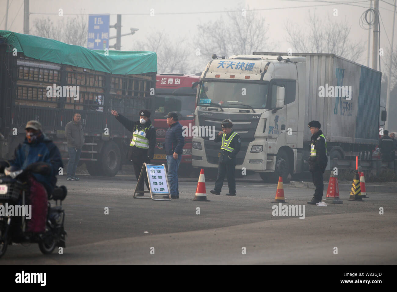 --FILE--Chinese traffic administration officers direct trucks and vans on a highway in heavy smog in Beijing, China, 4 December 2016.  Beijing's envir Stock Photo