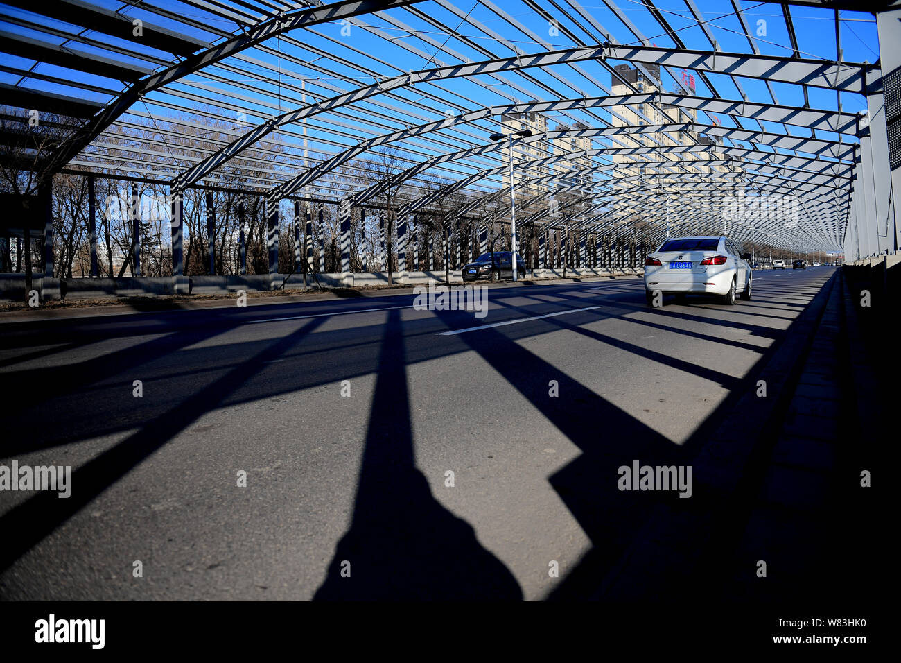 Vehicles travel on an elevated road fully covered by noise-reduction shelters in Shenyang city, northeast China's Liaoning province, 5 December 2016. Stock Photo