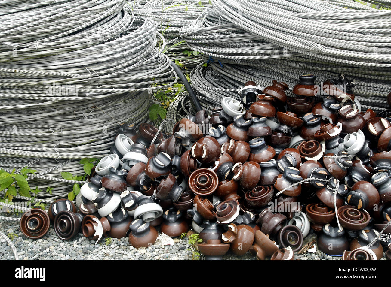 Photo of rolls of metal or steel cables and insulators used for electric poles at an industrial yard Stock Photo