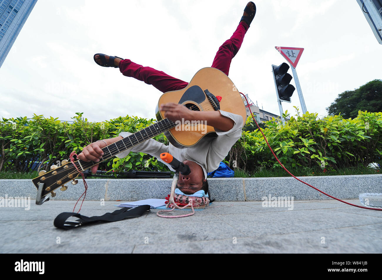 Chinese singer Yu Heqing headstands and performs on the street in Nanning city, south China's Guangxi Zhuang Autonomous Region, 6 November 2016.   A C Stock Photo