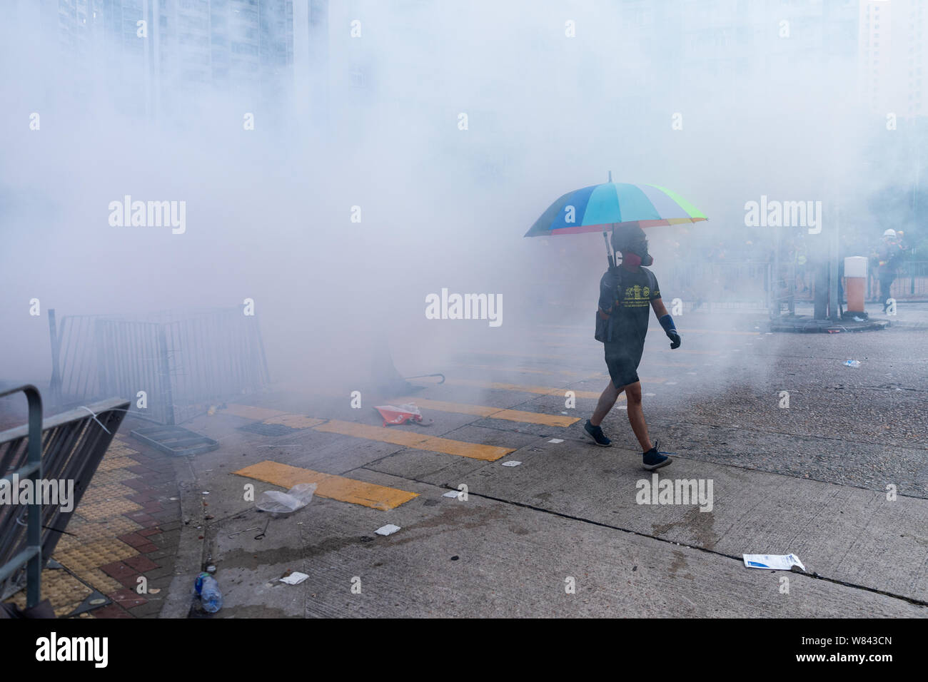 Hong Kong 5th August 2019. A protester strolls through a cloud of tear smoke holding a colourful umbrella as tear gas is being used  in an attempt to clear protesters in Wong Tai Sin, during a general strike in Hong Kong. Credit: David Coulson/Alamy Live News Stock Photo
