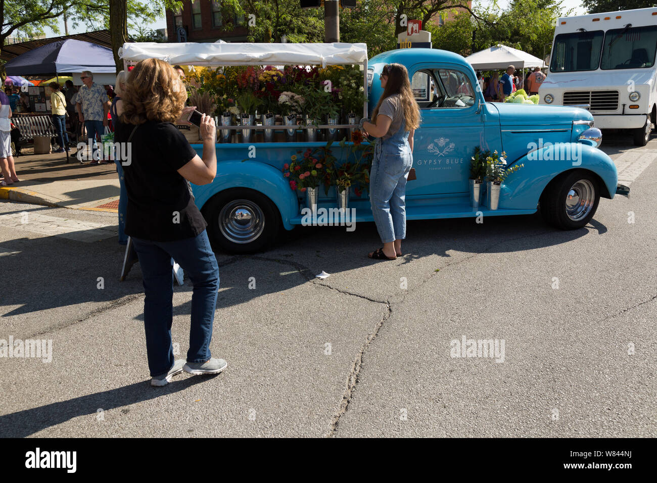 A customer photographs Gypsy Blue Flowers' beautiful classic flower truck at Fort Wayne's Farmers' Market in downtown Fort Wayne, Indiana, USA. Stock Photo