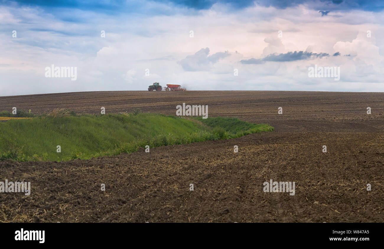Farmer seeding, sowing crops at field. Sowing is the process of planting seeds in the ground as part of the early spring time agricultural activities. Stock Photo