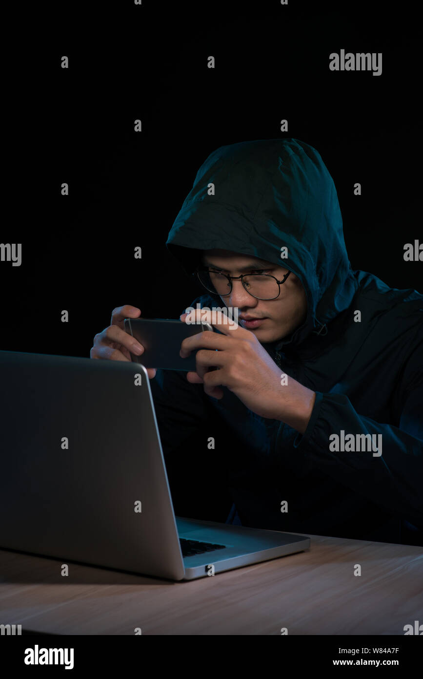 Hacker using a smartphone. Very dark nocturnal environment Stock Photo