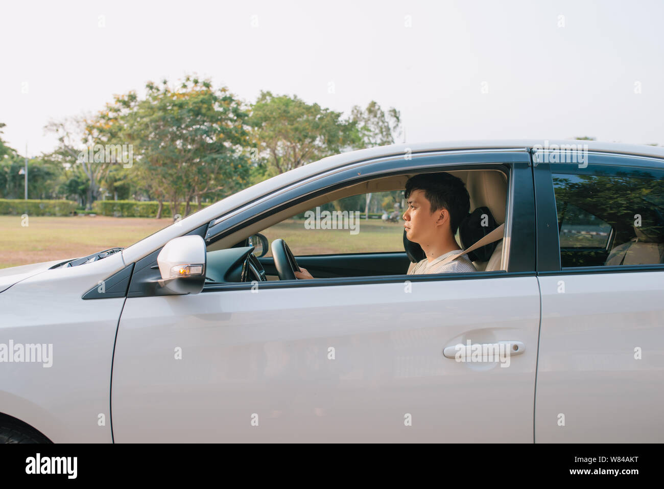 Riding his new car. Side view of handsome young man driving his car and smiling Stock Photo