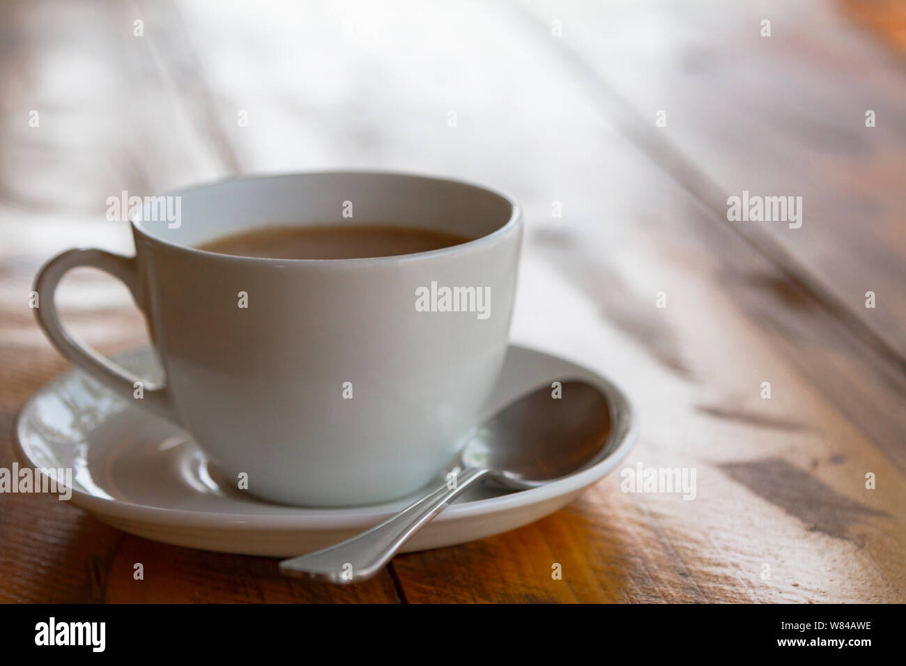 White cup of traditional indian tea masala with sauser and spon on wooden background. Close up. Stock Photo