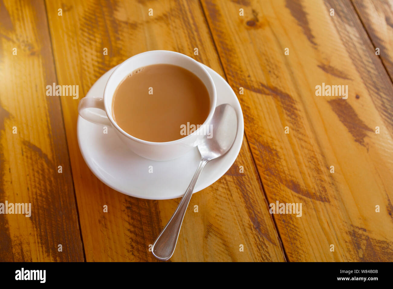 White cup of traditional indian tea masala with sauser and spon on wooden background. Top view. Toned. Stock Photo