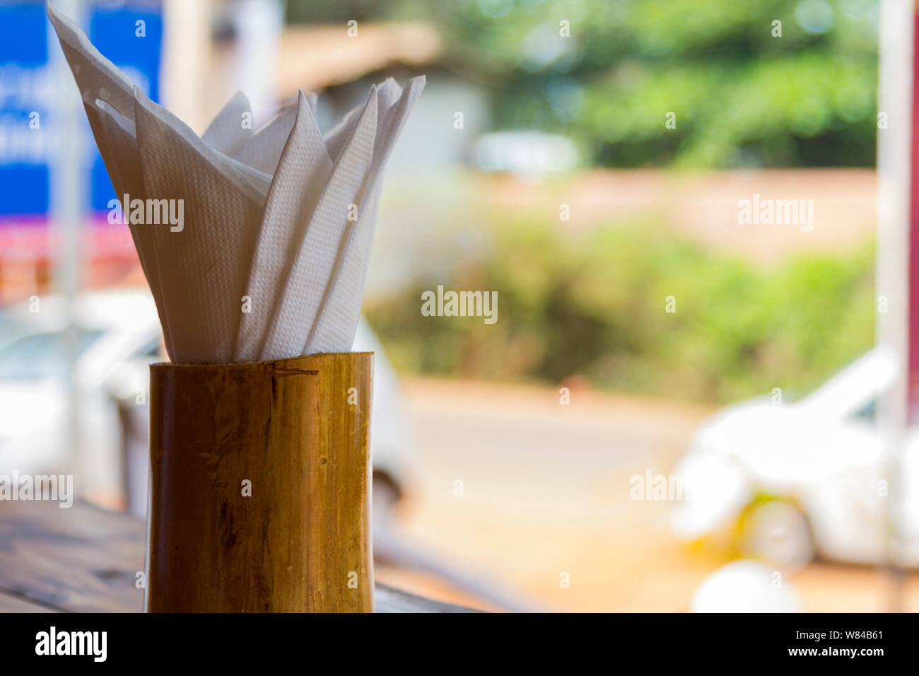 Wooden napkin holder on table in open-door green blur background. Close up, selective focus. Stock Photo