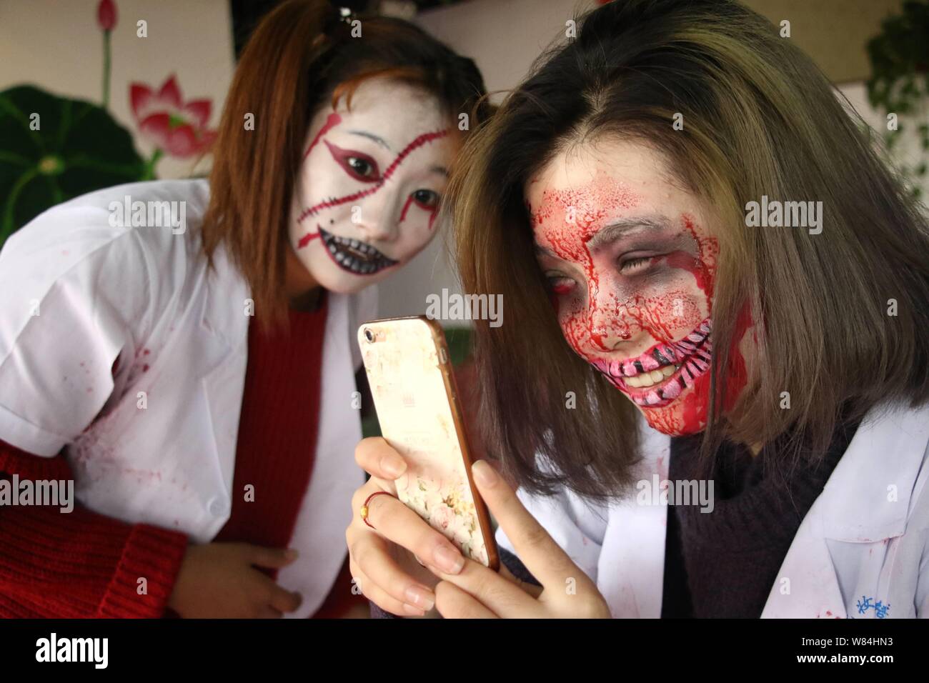 Young women with zombie makeups take a selfie during a gathering to celebrate Halloween at a barbecue restaurant in Binzhou city, east China's Shandon Stock Photo