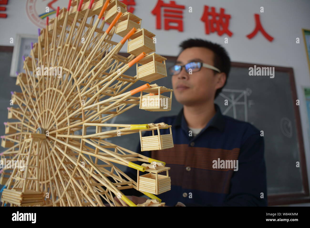 Chinese physics teacher Guo Liang looks at his homemade model Ferris wheel out of disposable chopsticks and toothpicks in the classroom at Feixiang Di Stock Photo