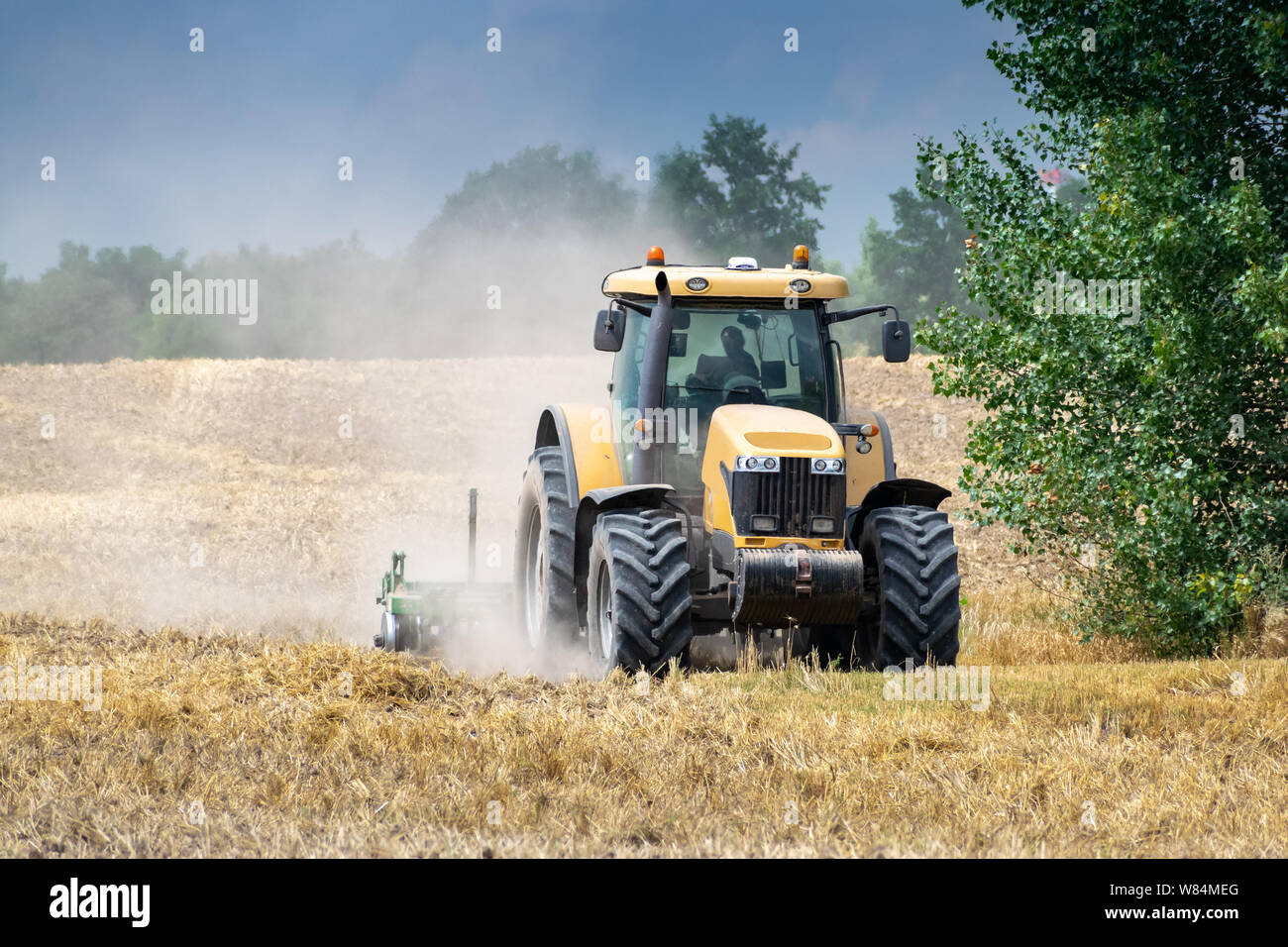 Tractor cultivating the field after harvesting of wheat Stock Photo - Alamy