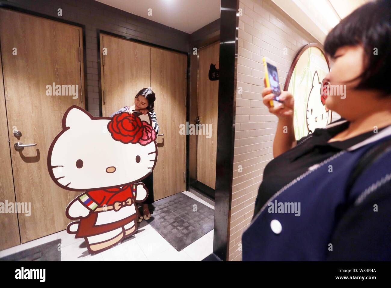 A girl poses for photos with a Hello Kitty cutout placard in the toilet  area at the Hello Kitty hot-pot restaurant in Shanghai, China, 19 October  2016 Stock Photo - Alamy, image size:1300x956