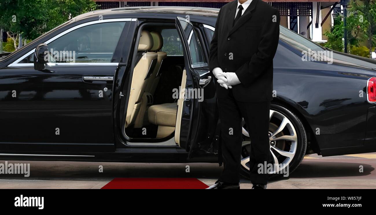 Driver standing next to opened car door with red carpet Stock Photo