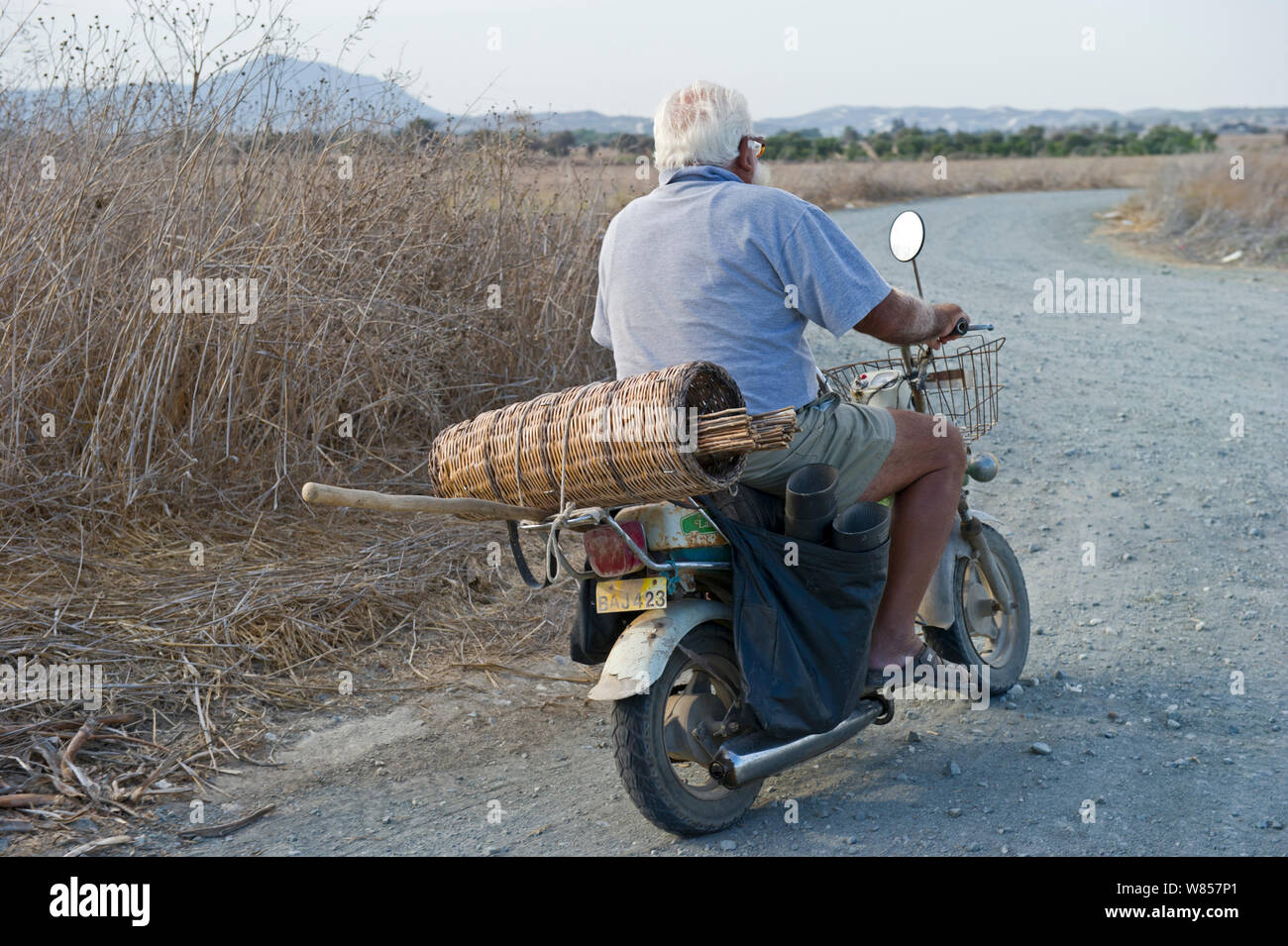 Illegal trapper with limesticks on back of motorcycle going to orchard to set up Cyprus, September 2011 Stock Photo