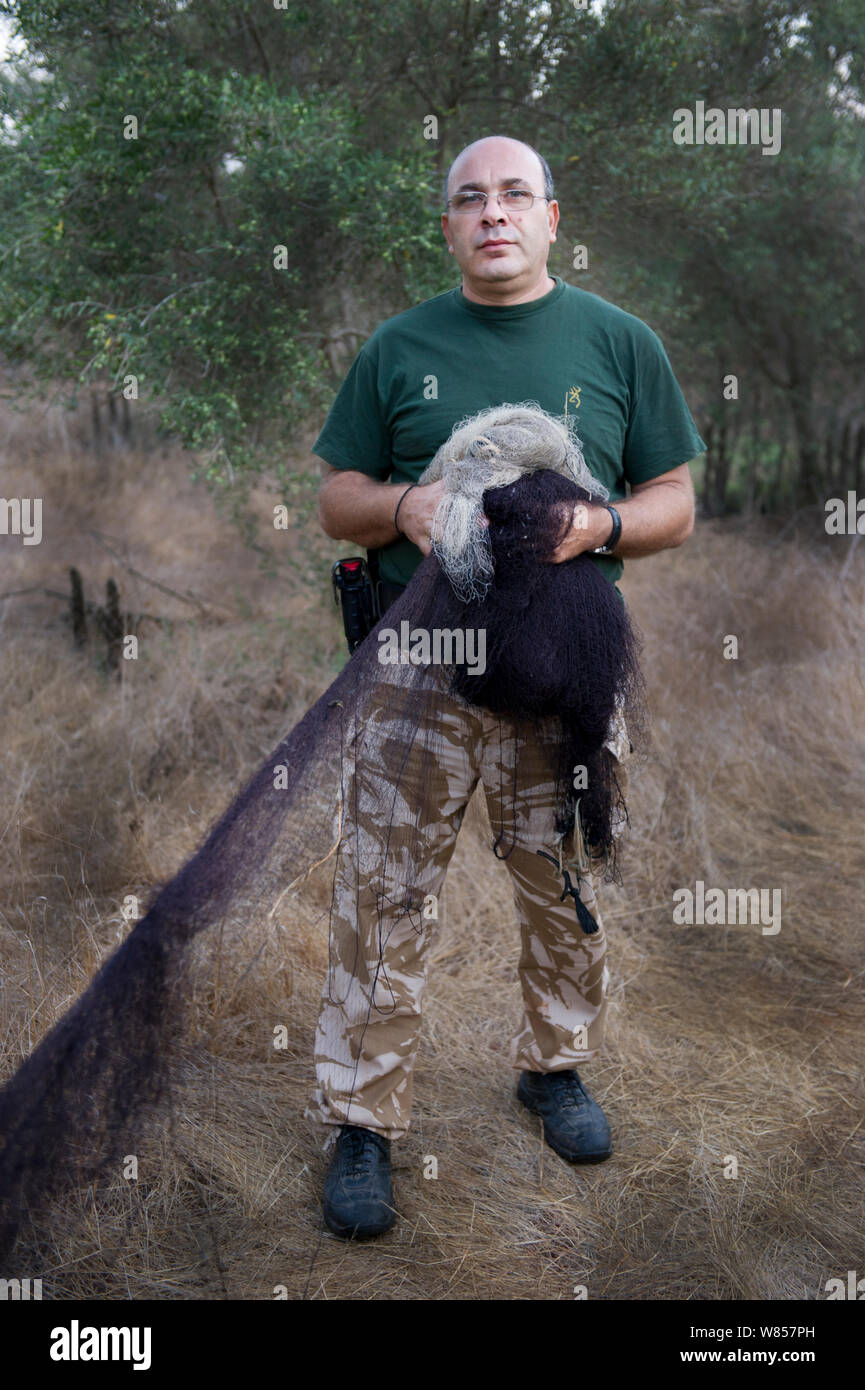 Police officer dismantles illegal mist nets in olive grove in Dekelia Sovereign Base Area of Cyprus, Birds would have been trapped and sold as the food delicacy ambelopoulia. September 2011. Stock Photo